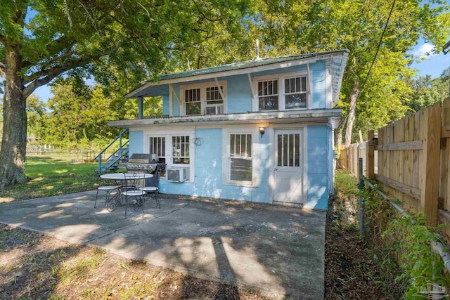 rear view of house with concrete block siding, fence, and a patio