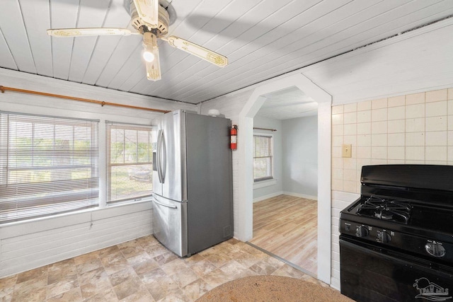 kitchen featuring stainless steel fridge with ice dispenser, baseboards, a ceiling fan, black gas range oven, and arched walkways