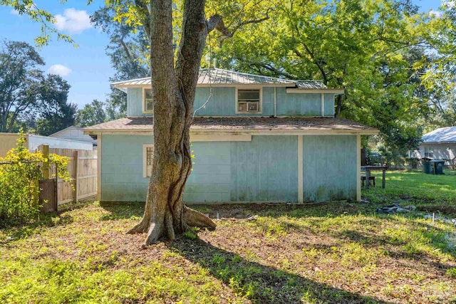 view of home's exterior with a yard, metal roof, and fence