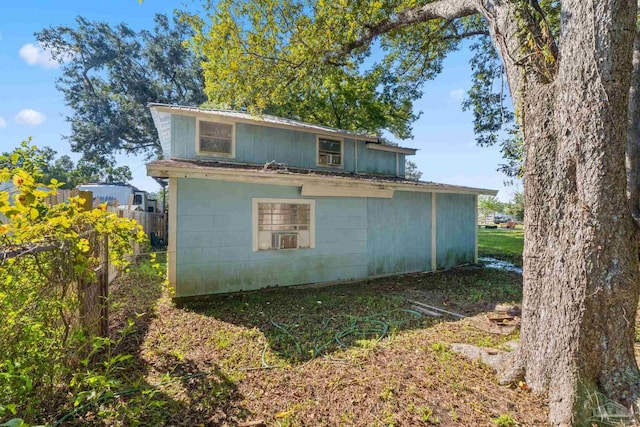 rear view of property with concrete block siding and fence