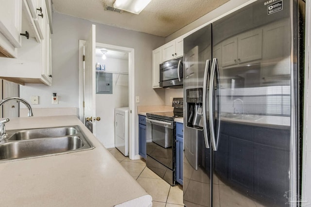 kitchen featuring washer / clothes dryer, white cabinetry, light tile patterned floors, sink, and stainless steel appliances