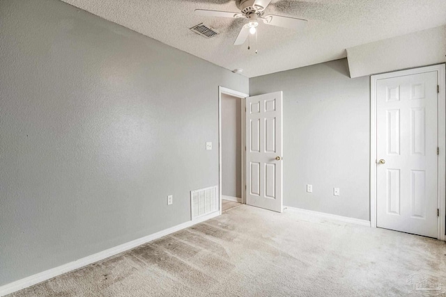 unfurnished bedroom featuring a textured ceiling, light colored carpet, and ceiling fan