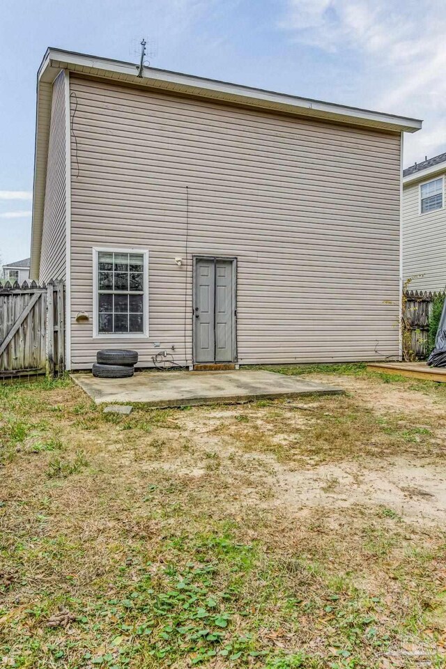 rear view of property featuring a lawn and a patio