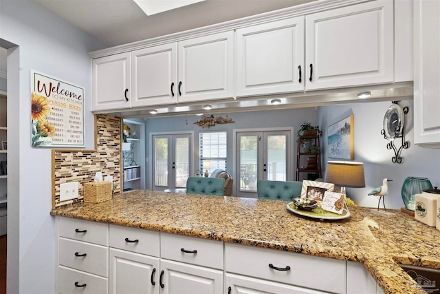 kitchen featuring tasteful backsplash, french doors, white cabinetry, light stone counters, and kitchen peninsula