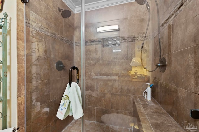 bathroom with a shower with shower door and ornamental molding