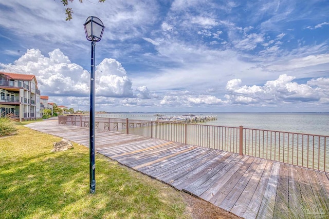 dock area featuring a lawn and a deck with water view