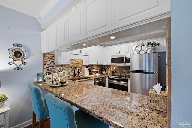 kitchen featuring sink, dark stone countertops, tasteful backsplash, white cabinetry, and stainless steel appliances