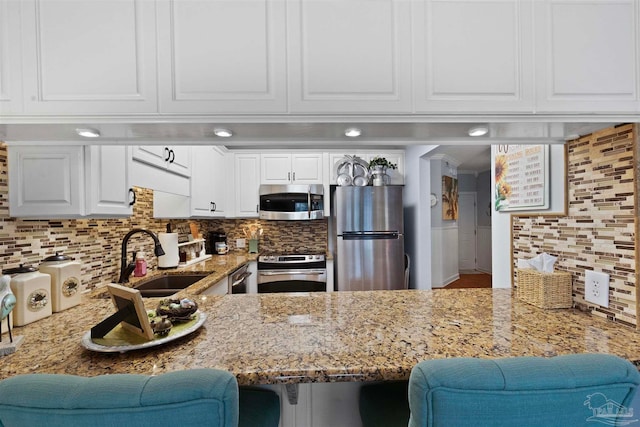 kitchen with sink, stainless steel appliances, decorative backsplash, and white cabinets