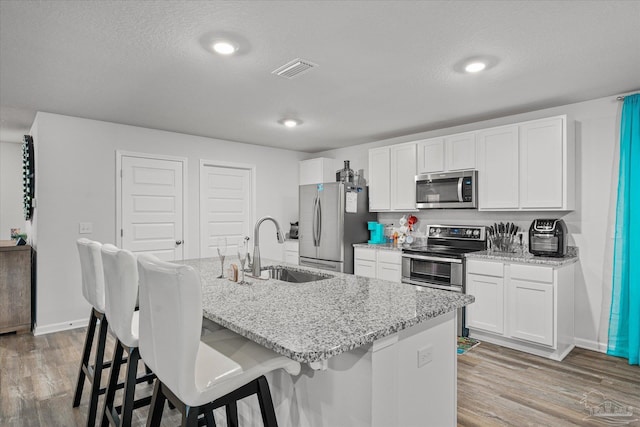 kitchen with a center island with sink, a kitchen bar, sink, stainless steel appliances, and white cabinets