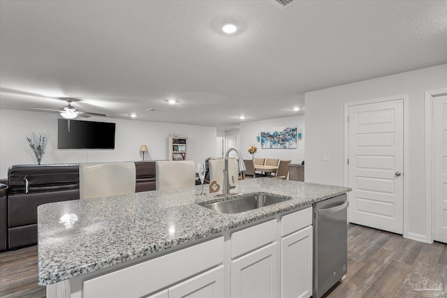 kitchen with a center island with sink, dark hardwood / wood-style floors, stainless steel dishwasher, white cabinets, and sink