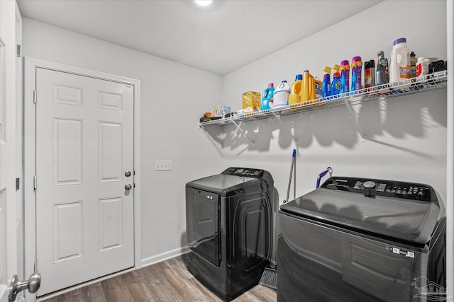 washroom with hardwood / wood-style floors, a textured ceiling, and washing machine and clothes dryer