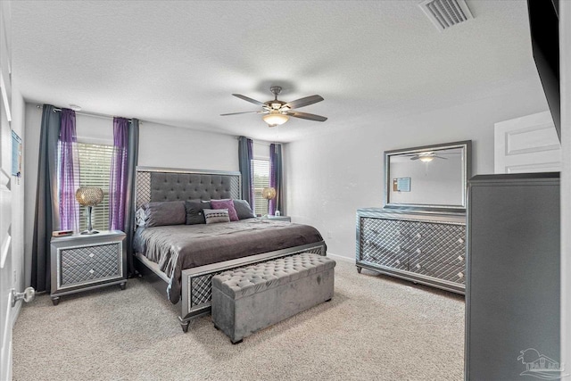 carpeted bedroom featuring ceiling fan, multiple windows, and a textured ceiling