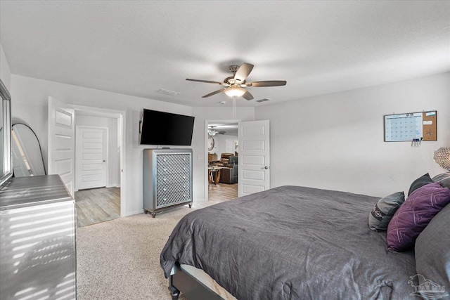 bedroom with light carpet, ceiling fan, and a textured ceiling