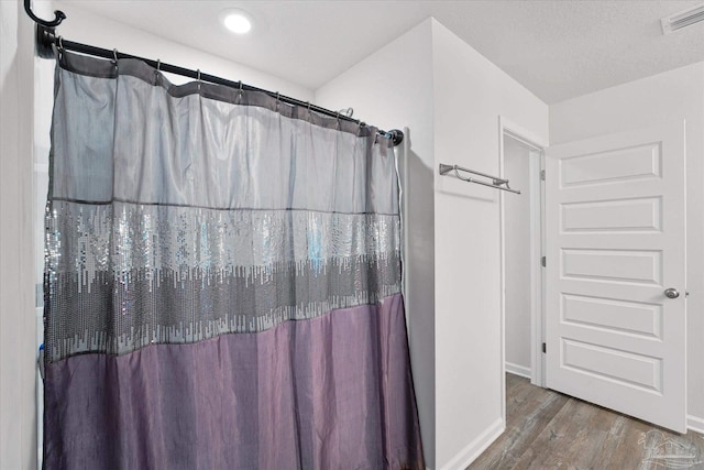 bathroom with hardwood / wood-style flooring and walk in shower