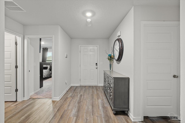 foyer entrance with a textured ceiling and light hardwood / wood-style flooring