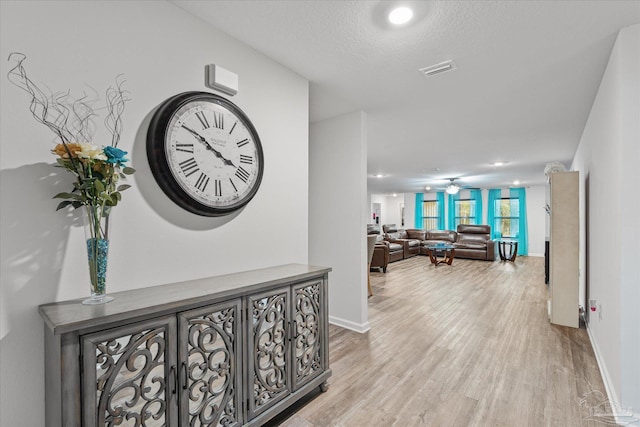 hall featuring a textured ceiling and light hardwood / wood-style floors