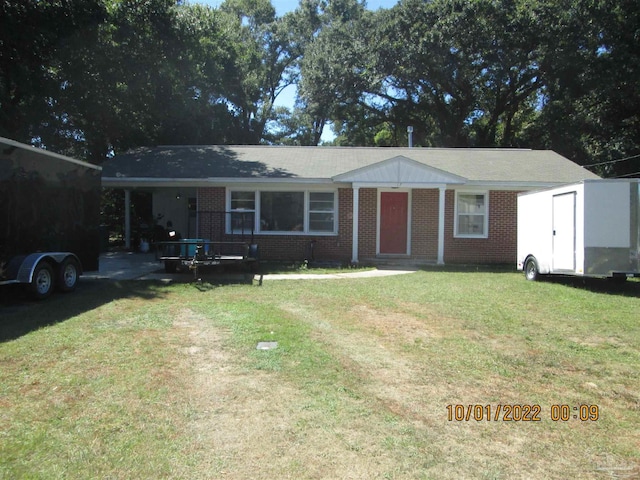 ranch-style home featuring a front lawn and a storage unit