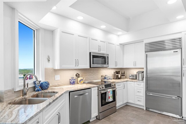 13335 Johnson Beach Rd Unit 1003, Pensacola, FL 32507 - kitchen featuring white cabinetry, sink, backsplash, light stone counters, and appliances with stainless steel finishes