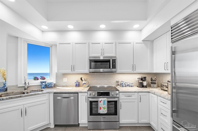 13335 Johnson Beach Rd Unit 1003, Pensacola, FL 32507 - kitchen featuring sink, a water view, white cabinetry, stainless steel appliances, and decorative backsplash