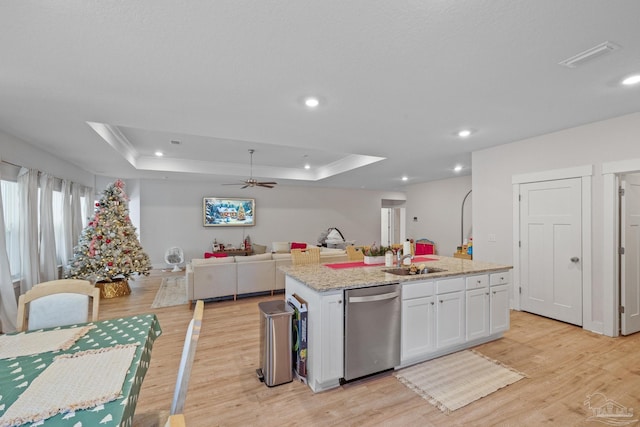 kitchen featuring stainless steel dishwasher, white cabinetry, a kitchen island with sink, and a tray ceiling