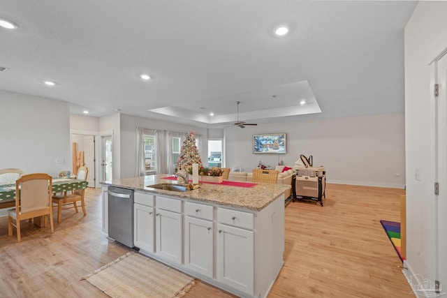 kitchen featuring dishwasher, a kitchen island with sink, a tray ceiling, white cabinets, and sink