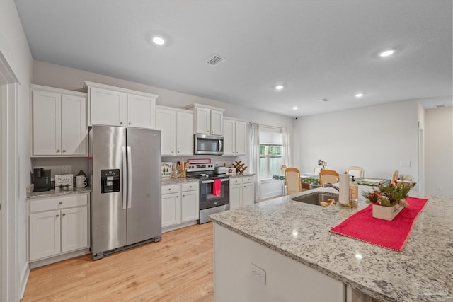 kitchen with sink, white cabinetry, light hardwood / wood-style flooring, light stone countertops, and appliances with stainless steel finishes