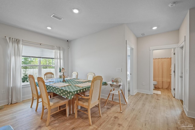 dining area featuring a textured ceiling and light hardwood / wood-style flooring