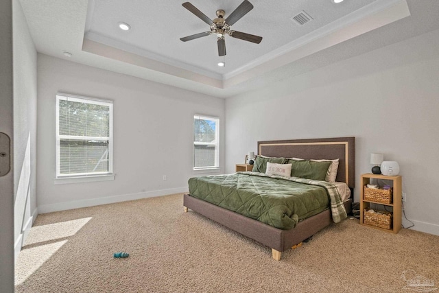 carpeted bedroom with ceiling fan, crown molding, and a raised ceiling