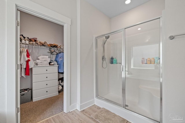 bathroom with a shower with shower door and hardwood / wood-style flooring