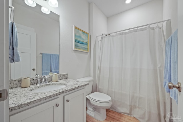 bathroom with toilet, hardwood / wood-style flooring, walk in shower, and vanity