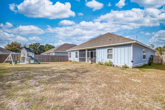 back of property featuring a yard and a playground