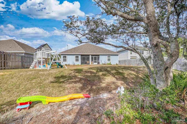 rear view of house with a lawn and a playground