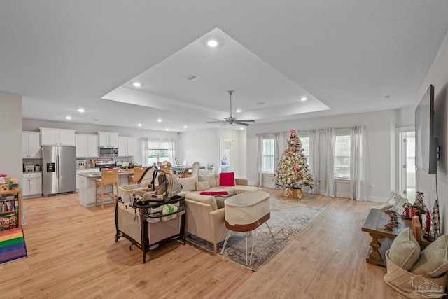 living room featuring light hardwood / wood-style floors, ceiling fan, and a raised ceiling