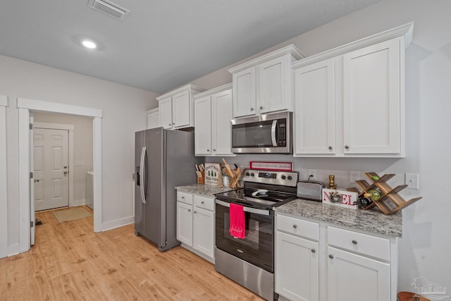 kitchen with light stone countertops, white cabinets, light wood-type flooring, and appliances with stainless steel finishes