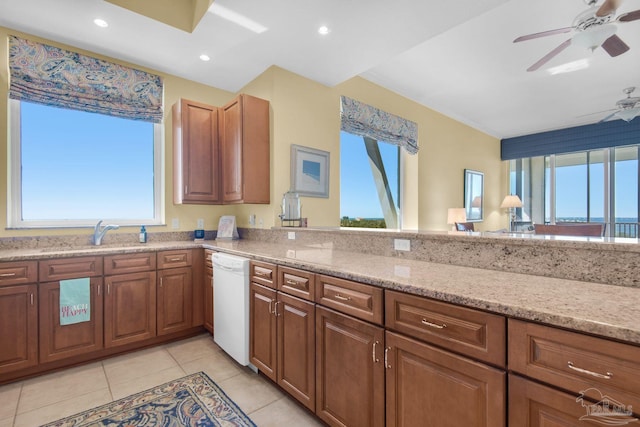 kitchen with white dishwasher, sink, light tile patterned floors, light stone counters, and ceiling fan