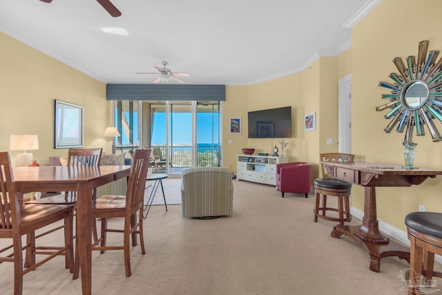 dining space featuring ornamental molding, light carpet, and ceiling fan