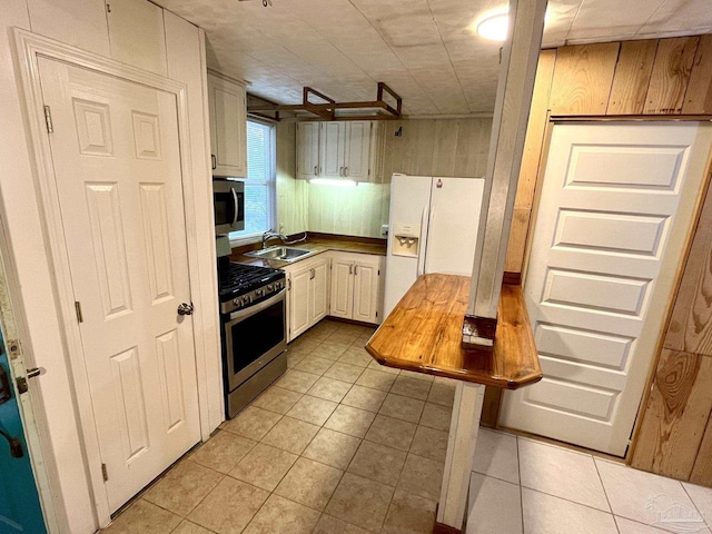 kitchen featuring light tile patterned floors, appliances with stainless steel finishes, and a sink