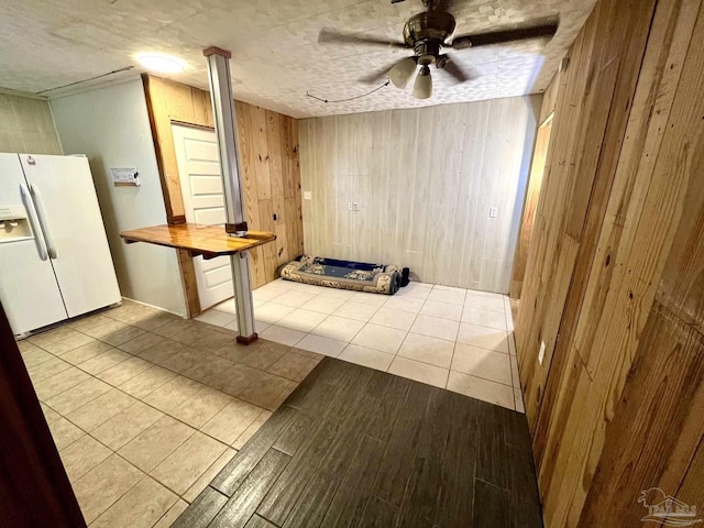 interior space with wood finished floors, a ceiling fan, and wooden walls