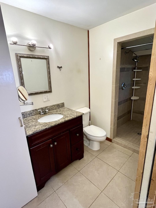 bathroom featuring a tile shower, vanity, toilet, and tile patterned floors