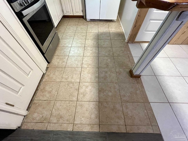 interior details featuring fridge, stove, and white cabinets