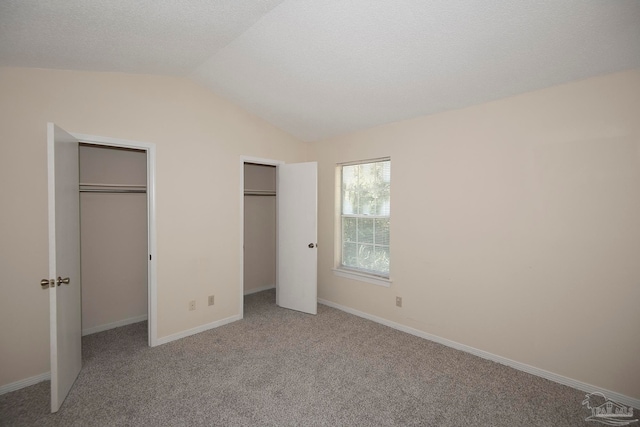 unfurnished bedroom featuring light colored carpet and lofted ceiling