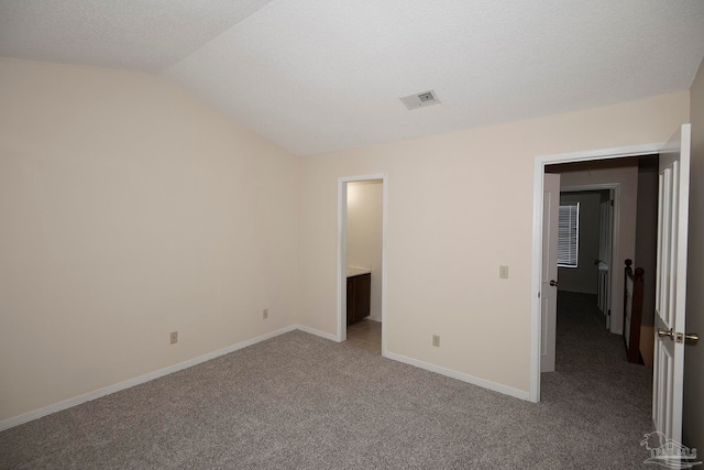 unfurnished bedroom with light colored carpet, a textured ceiling, and lofted ceiling