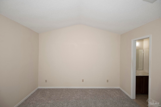 unfurnished room with a textured ceiling, light carpet, and vaulted ceiling