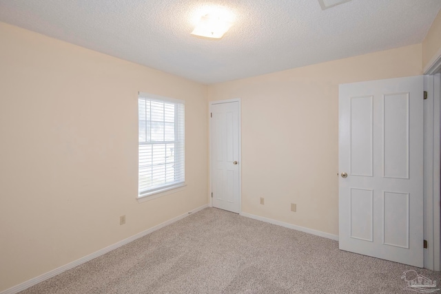 unfurnished room featuring a textured ceiling and light carpet