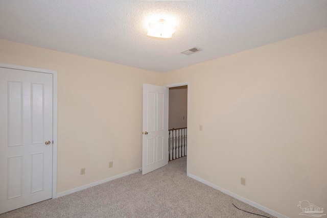 carpeted spare room featuring a textured ceiling