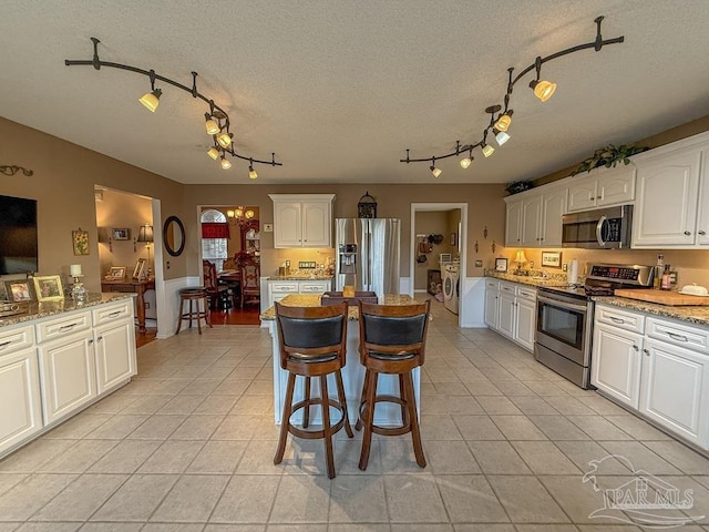 5020 Lantana Dr, Gulf Breeze, FL 32563 - kitchen featuring stainless steel appliances, rail lighting, light tile patterned floors, light stone counters, and white cabinets