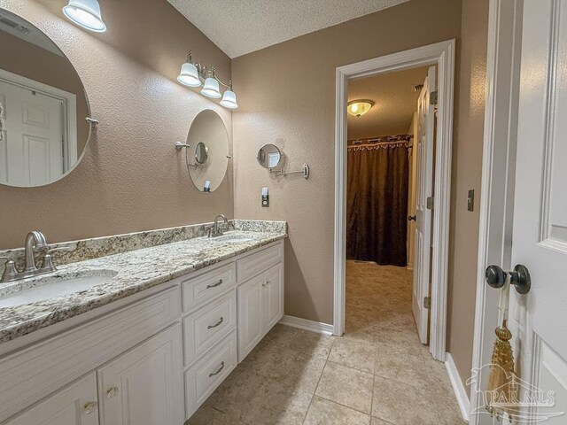 5020 Lantana Dr, Gulf Breeze, FL 32563 - bathroom with tile patterned floors, double vanity, baseboards, and a textured ceiling