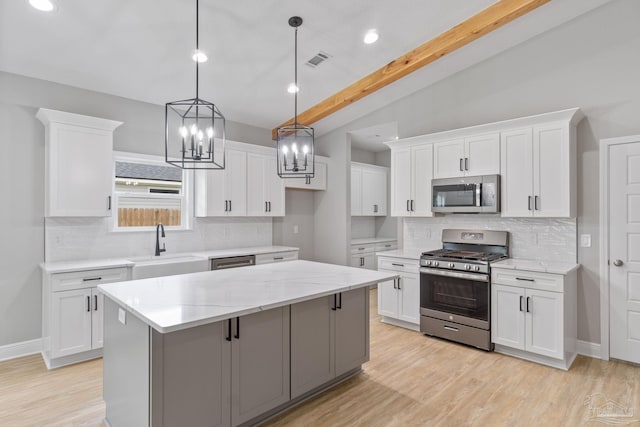 kitchen featuring appliances with stainless steel finishes, lofted ceiling with beams, sink, white cabinets, and a center island