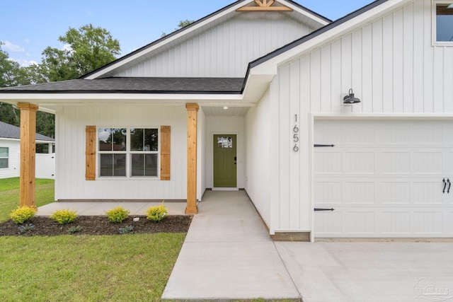 entrance to property with a garage, covered porch, and a lawn