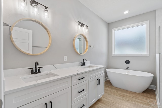 bathroom with a tub to relax in, wood-type flooring, and vanity